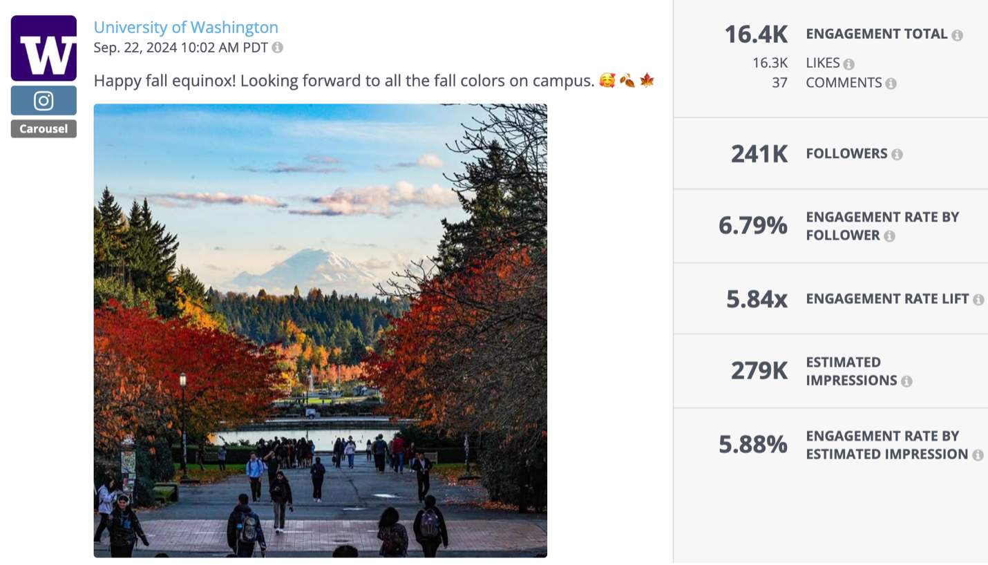 Students walk down a tree-lined path at the University of Washington during fall, with red and orange foliage surrounding the scene and Mount Rainier visible in the distance.